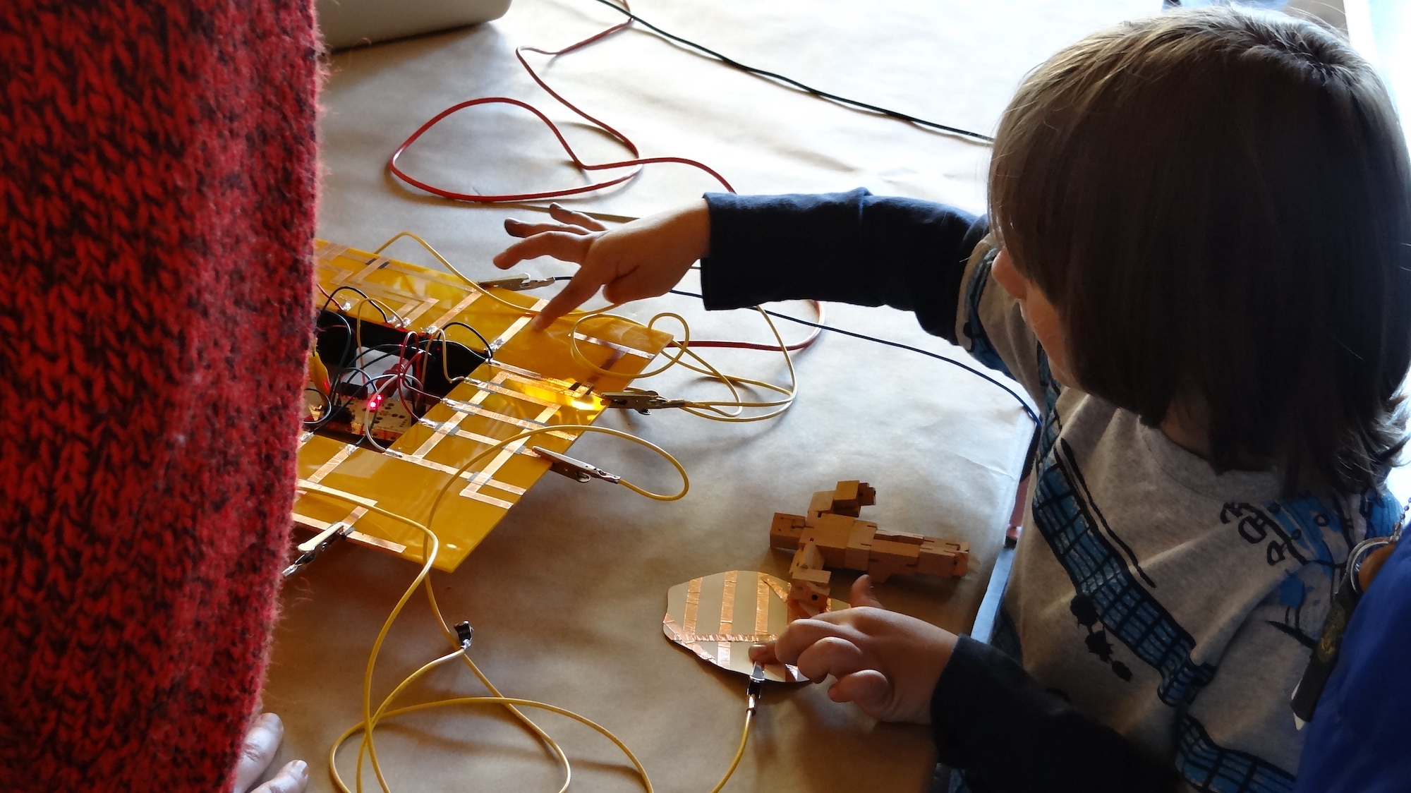 a young child using their finger to play with conductive circuits